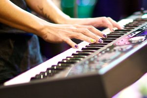 hands of musician playing keyboard in concert with shallow depth