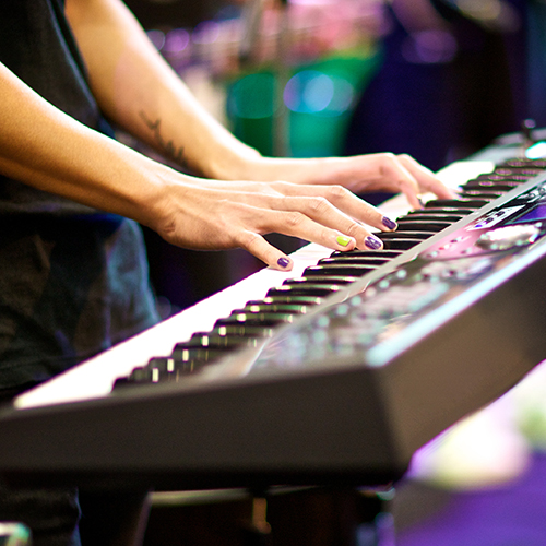 hands of musician playing keyboard in concert with shallow depth