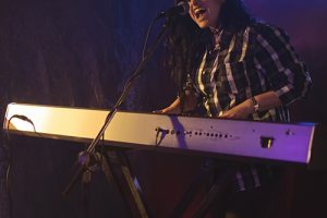 Singer and drummer performing in illuminated nightclub