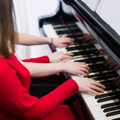 Teenage girls playing piano together